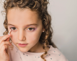 little girl applying children's eye shadow