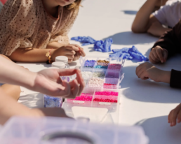 Kinder bei der Herstellung von Perlenketten