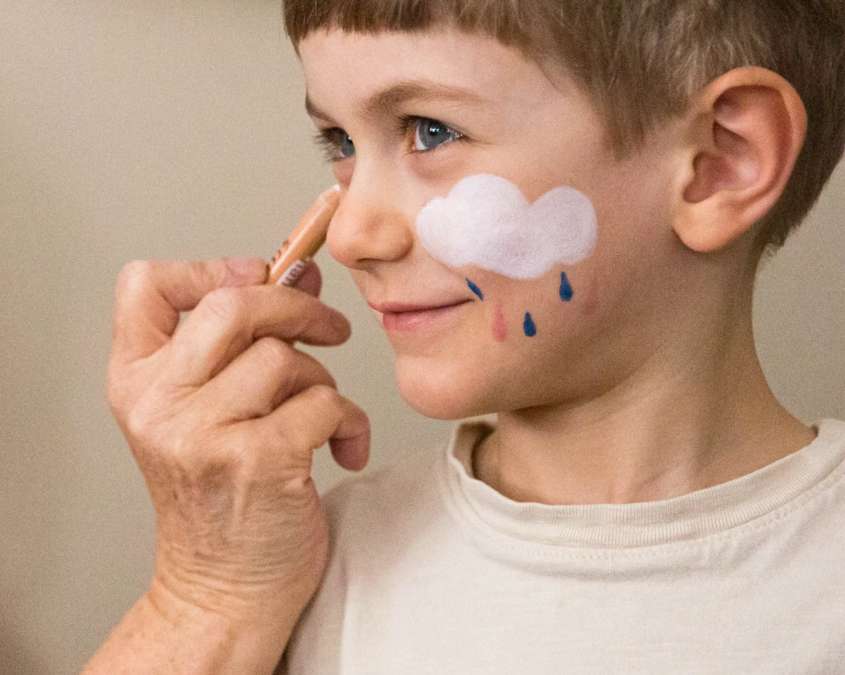grand mère appliquant du crayon de maquillage sur son petit fils